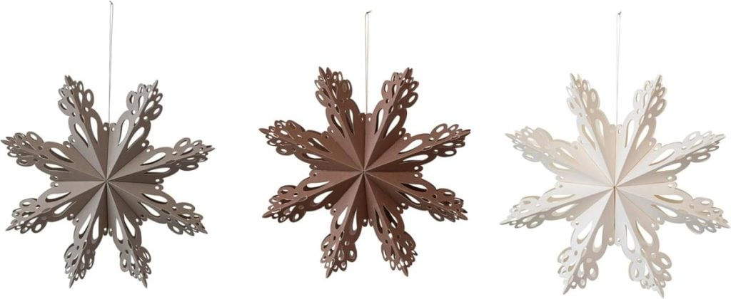 Three decorative paper snowflakes in shades of grey, brown, and white, each displaying intricate cutout designs, hanging against a plain background.