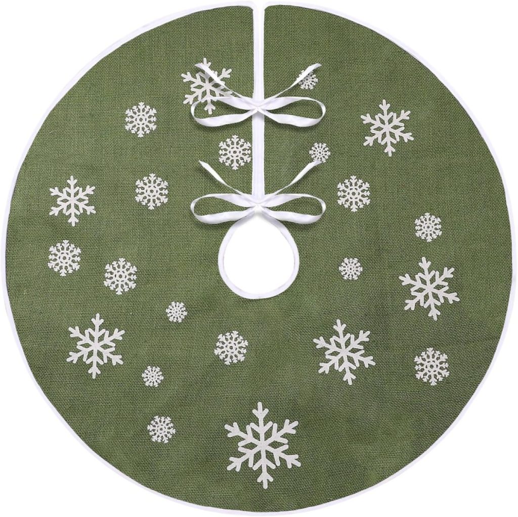 A green circular Christmas tree skirt adorned with white snowflake patterns and three elegant white ribbon ties.