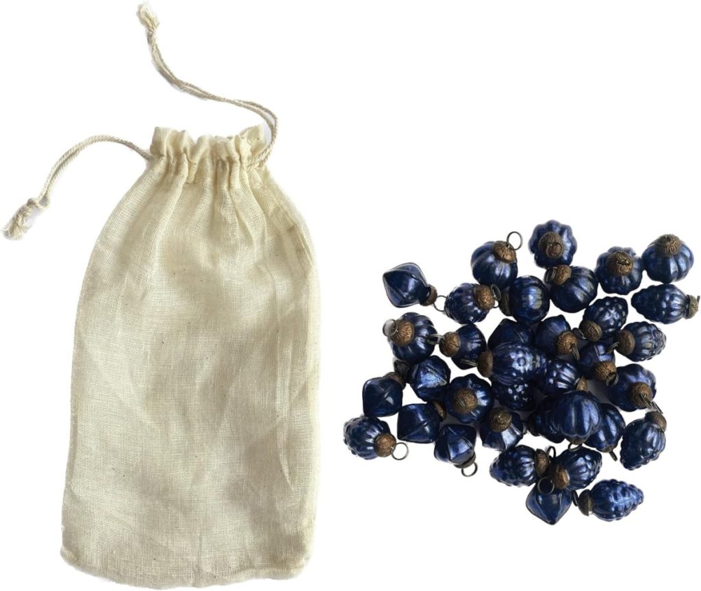 A beige drawstring pouch next to a pile of small blue decorative beads with metallic loop attachments, perfect for crafting or storing Vintage Christmas Ornaments.
