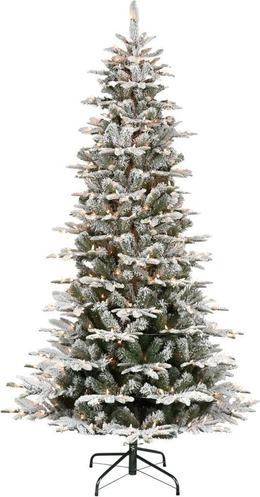 A tall artificial Christmas tree with frosted branches and white lights on a metal stand.