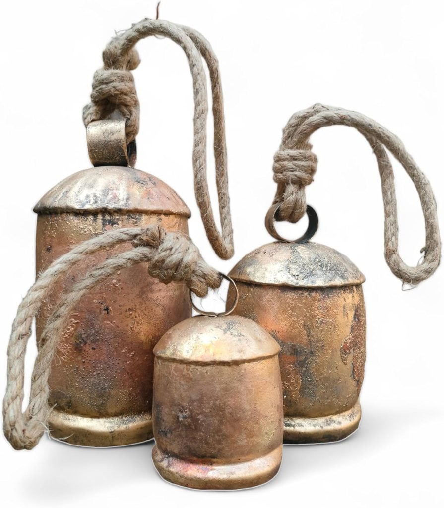 Three rustic, brass-colored bells with textured surfaces and thick rope handles evoke a sense of festive charm, subtly hinting at Christmas colors as they are displayed against a white background.