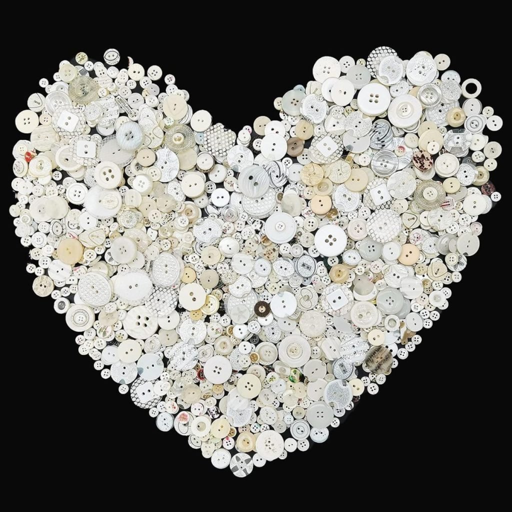 A heart shape crafted from an assortment of white and cream buttons on a black background showcases the art of button crafts.