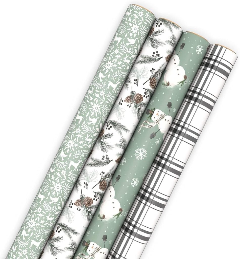 Four rolls of holiday-themed gift wrapping paper with different designs: green with white trees, pine cones, snowmen on green, and black and white plaid.