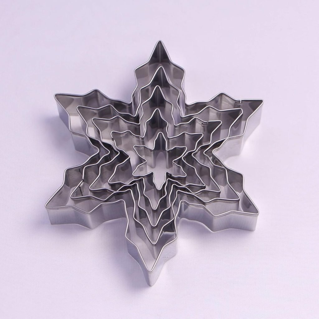 A set of nested metal snowflake-shaped cookie cutters on a white background, perfect for crafting delightful holiday desserts.