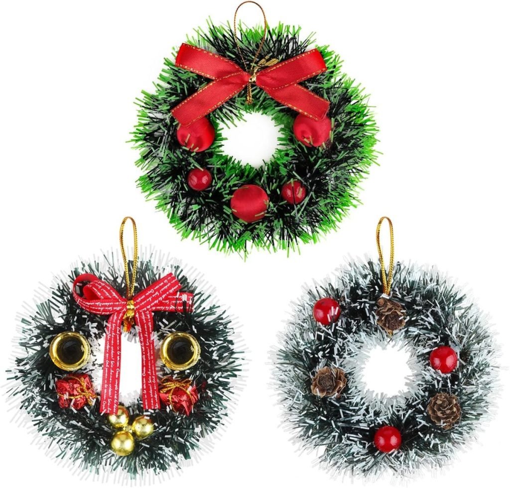 Three decorative wreaths with green foliage and red ornaments. One features a red bow and apples, another adorned with golden bells, while the last one includes pinecones, silver accents, and a festive Christmas ribbon.