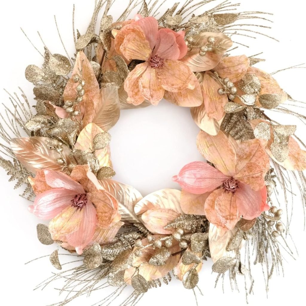 A Christmas wreath adorned with pink flowers, gold leaves, and glittery accents arranged in a circular pattern.