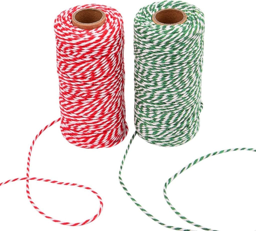 Two spools of twisted string, one red and white, the other green and white, are placed side by side with loose ends extending outward, perfect for button crafts.