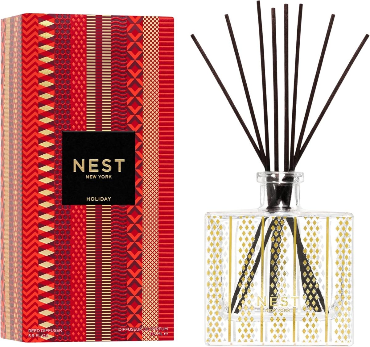 A NEST New York Holiday reed diffuser with decorative red and gold packaging beside a clear glass bottle holding black diffuser reeds—perfect for gifting or treating yourself this Black Friday.