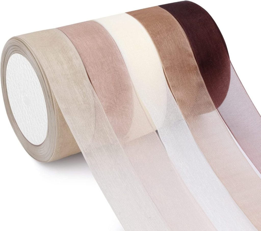 Four rolls of sheer organza ribbon in beige, brown, cream, and dark burgundy, unrolled to display their colors and texture—perfect to set a Christmas table with elegant, festive accents.