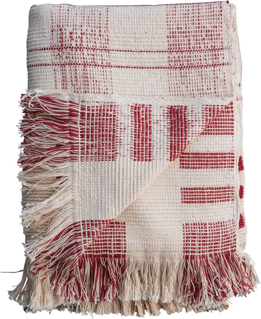 A folded woven throw blanket with a red and cream checkered pattern and fringed edges, perfect for adding cozy charm to your home during the holiday season.