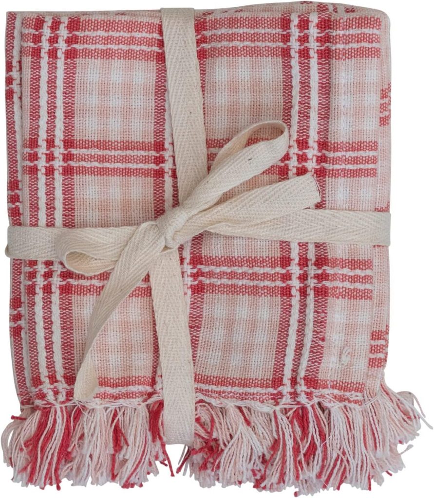 Folded red and white plaid towel with fringed edges, tied with a beige fabric ribbon—perfect for adding cozy charm to your pink Christmas décor.