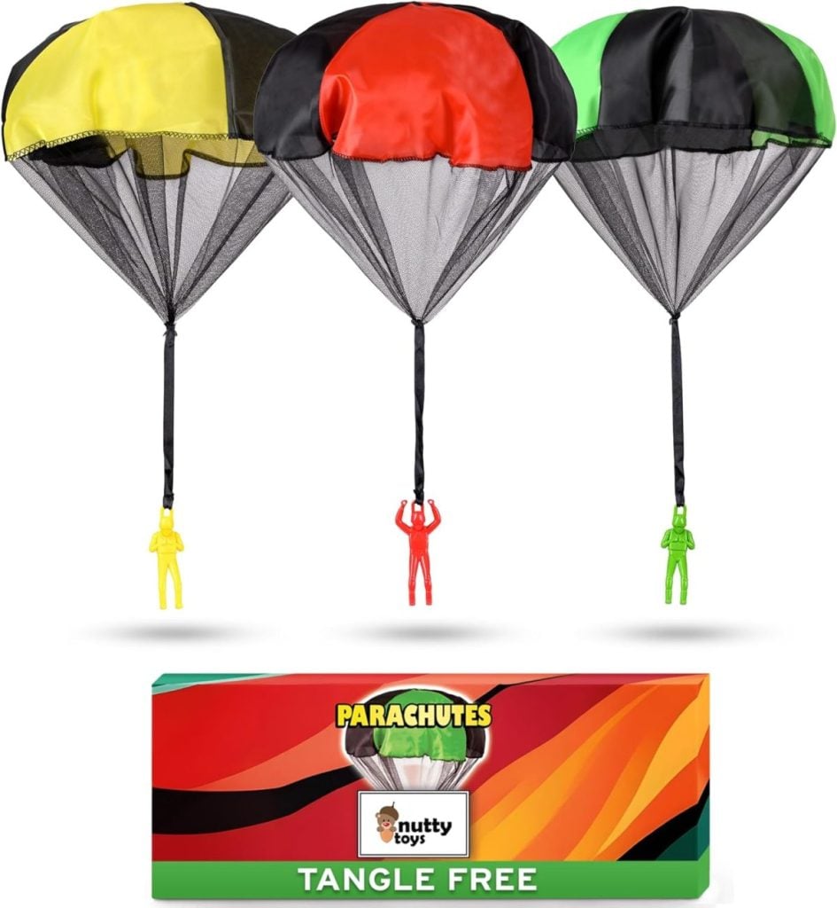 Three toy parachutes in yellow, red, and green with matching figurines soar above a colorful "PARACHUTES" and "TANGLE FREE" box by Nutty Toys—a perfect surprise for Christmas Morning.