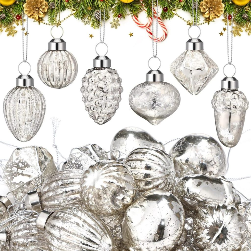 Silver glass Christmas ornaments of various shapes are arranged in a pile, with some hanging from a festive garland decorated with pinecones and candy canes—perfect to set a Christmas table with sparkling holiday charm.