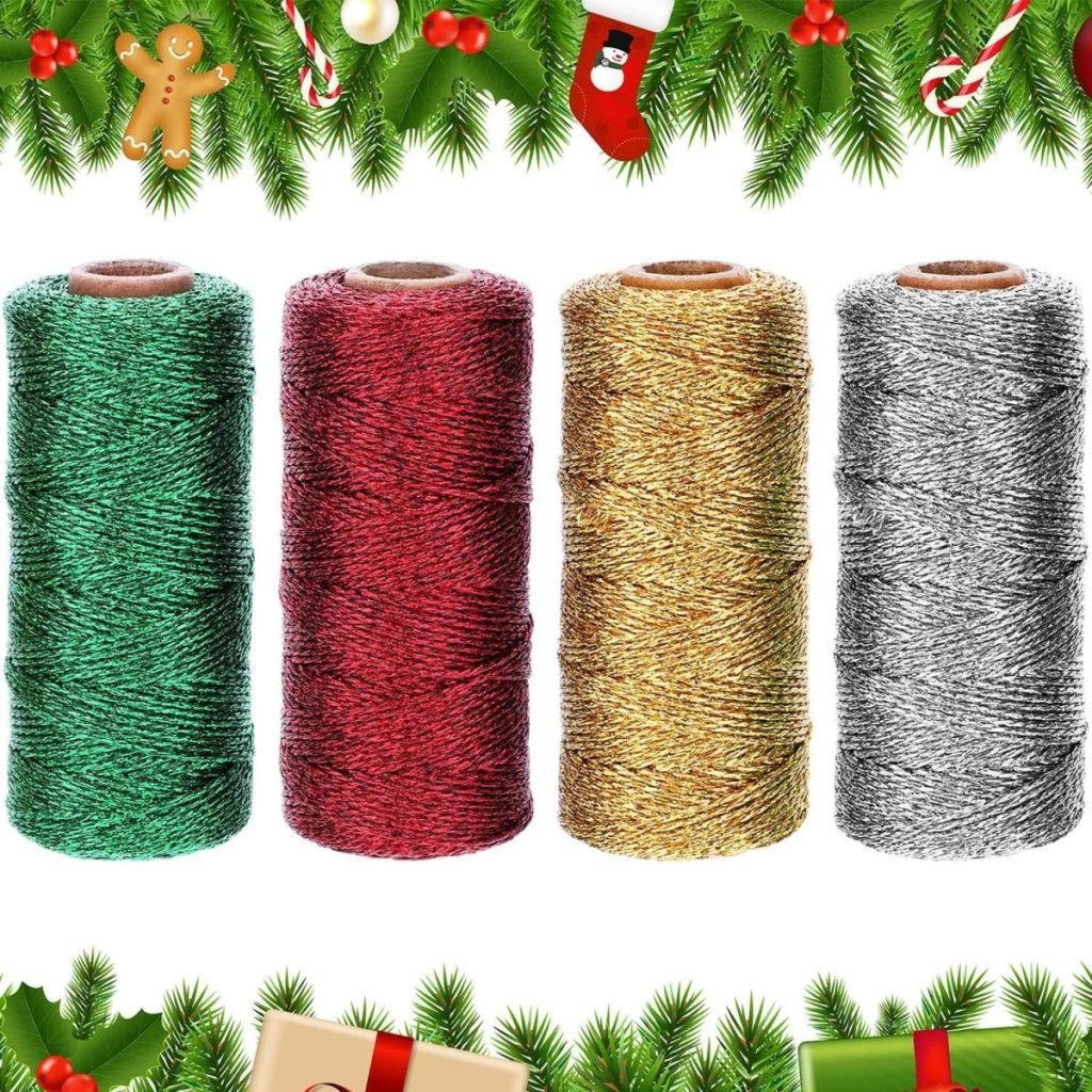 Four spools of metallic twine in green, red, gold, and silver, set against a festive border of greenery, ornaments, and gift boxes.