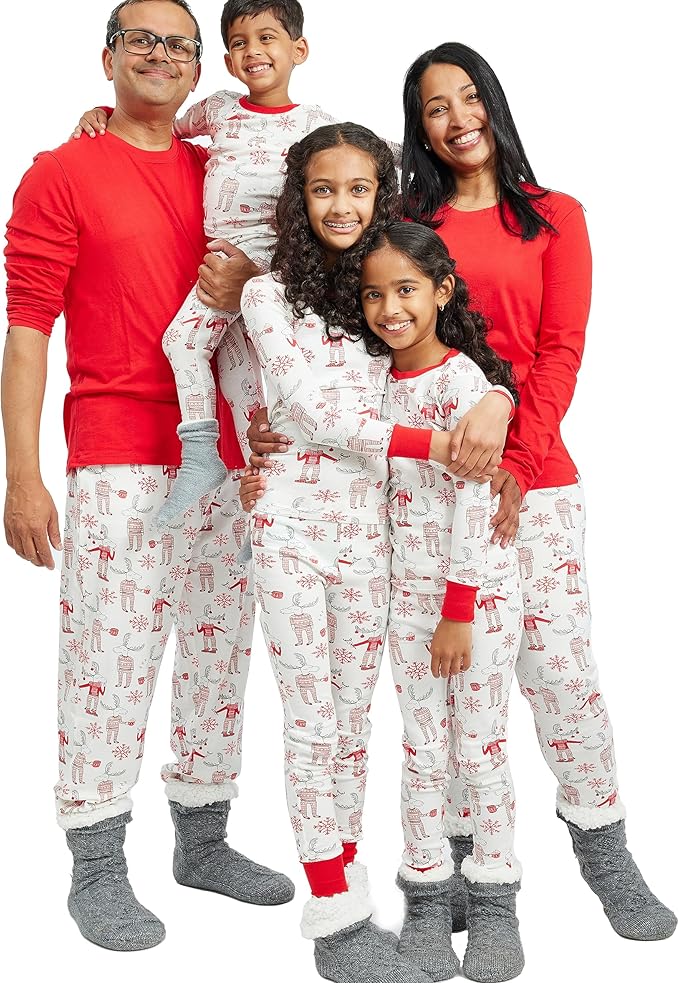 A family of five, clad in matching holiday-themed pajamas and grey socks, beams with joy against a white background, ready for Black Friday festivities.