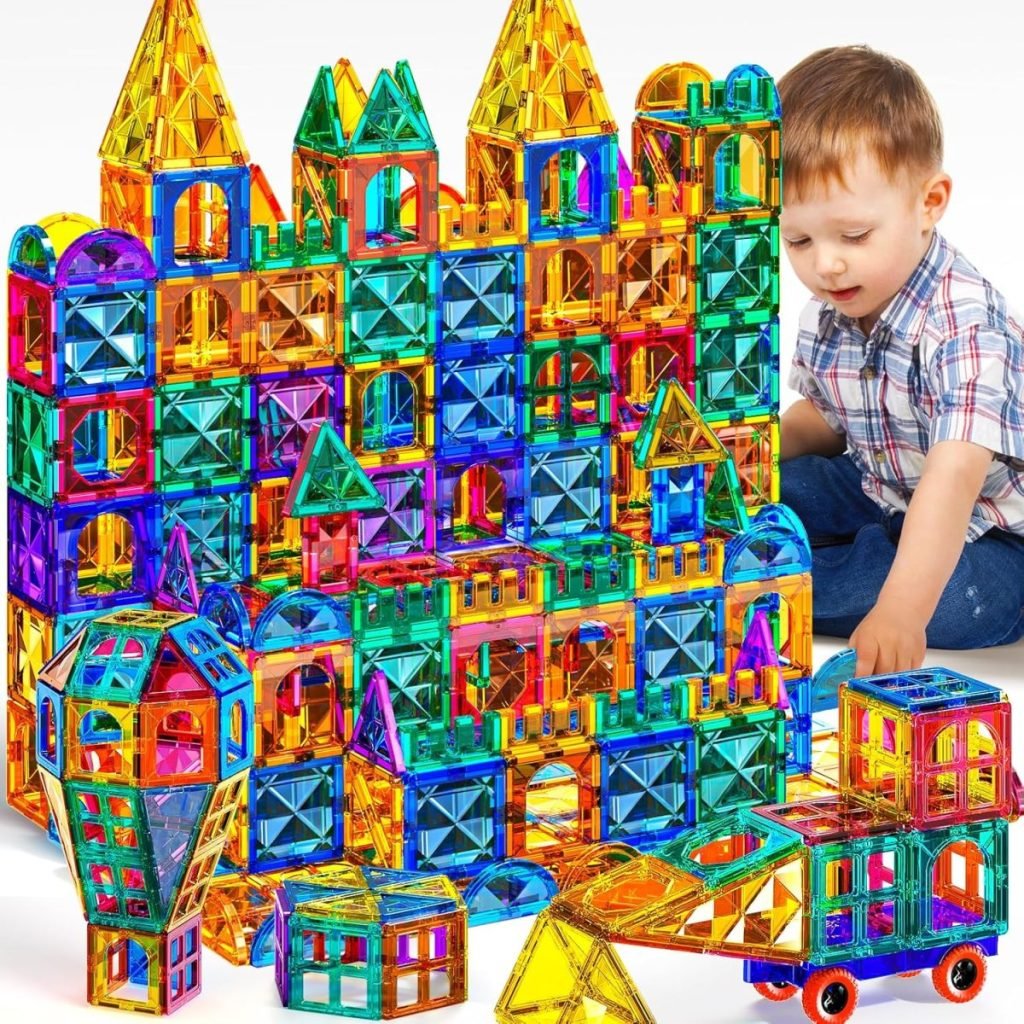 A child joyfully constructs a large castle-like structure with multicolored magnetic building tiles, embodying creativity against a crisp white background. This enchanting playtime scene could be the perfect Black Friday inspiration for holiday gift ideas.