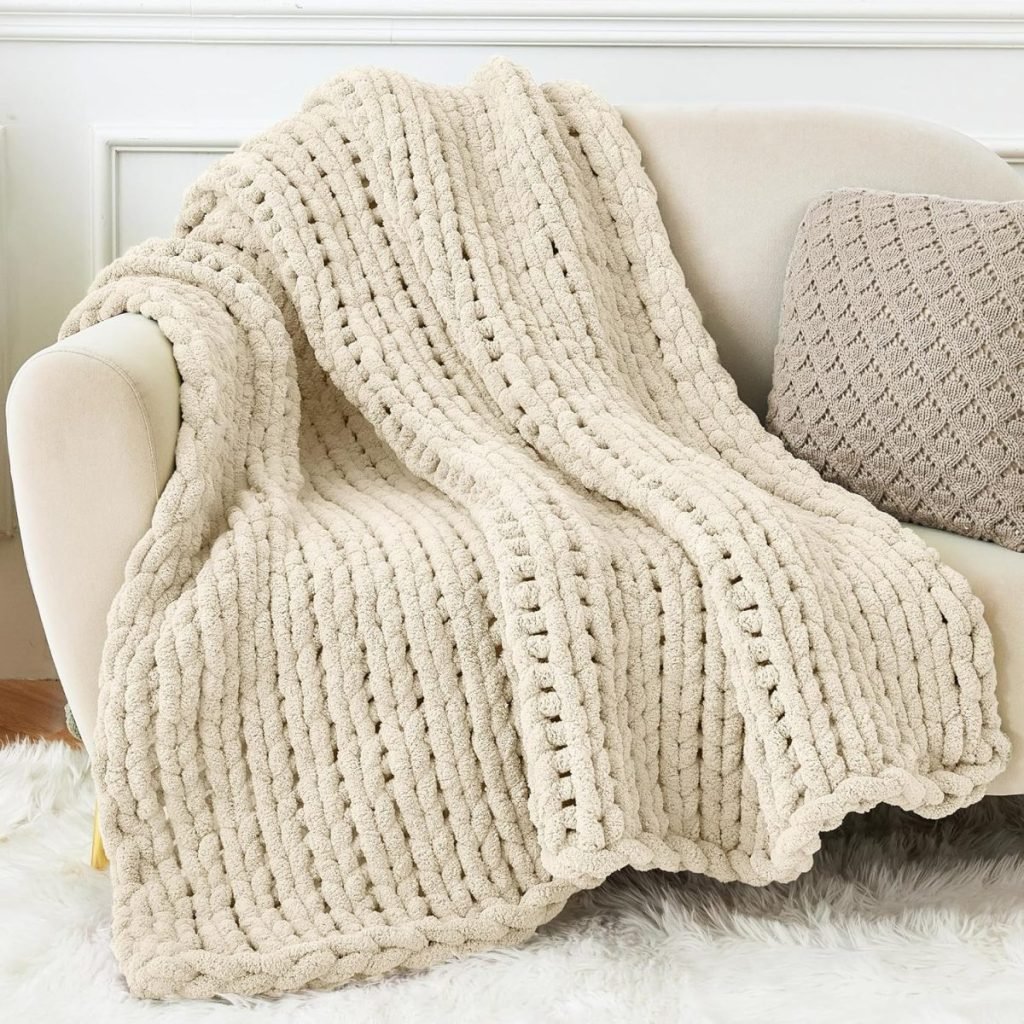 A cream-colored chunky knit blanket draped over a beige sofa, with a knitted cushion beside it, evokes the cozy charm of a nutcracker Christmas scene.