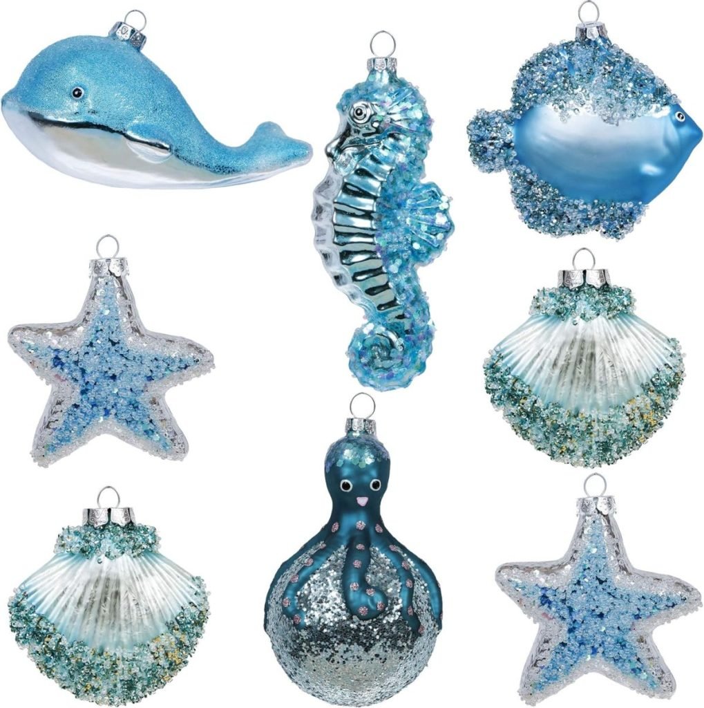 A collection of blue sea-themed Christmas ornaments, including a whale, seahorse, fish, starfish, seashells, and octopus, all adorned with glitter and sparkles.