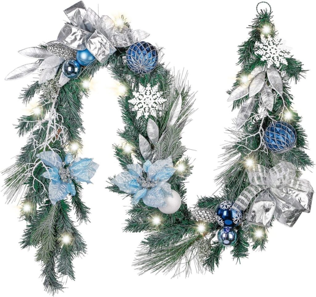 Festive garland decorated with Christmas colors, featuring silver leaves, blue and white flowers, pine cones, and ornaments, all beautifully adorned with small white lights.