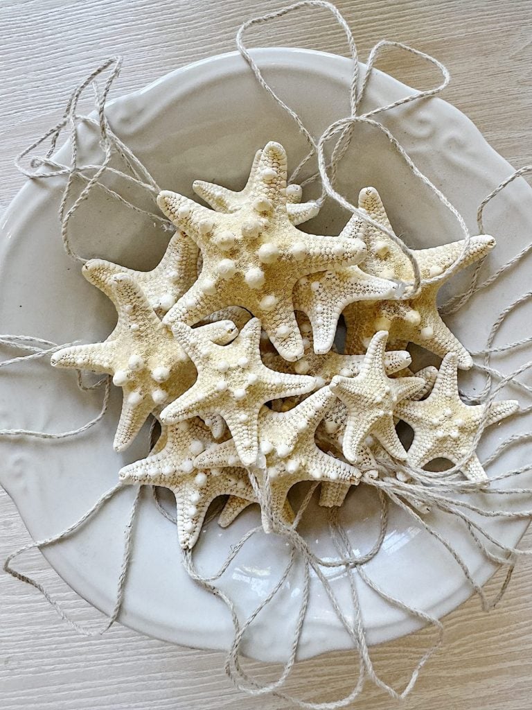 A white bowl filled with star-shaped decorative ornaments, each attached to a piece of twine.