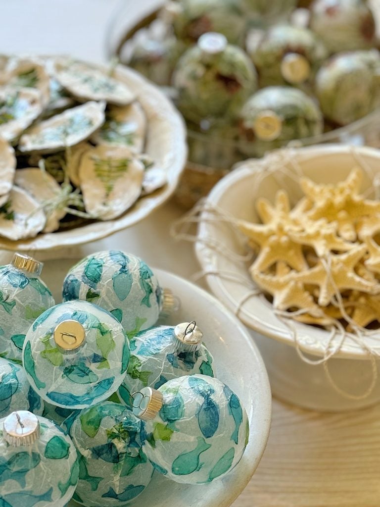 Colorful, marine-themed ornaments in bowls, including blue glass balls, starfish, and decorative shells.