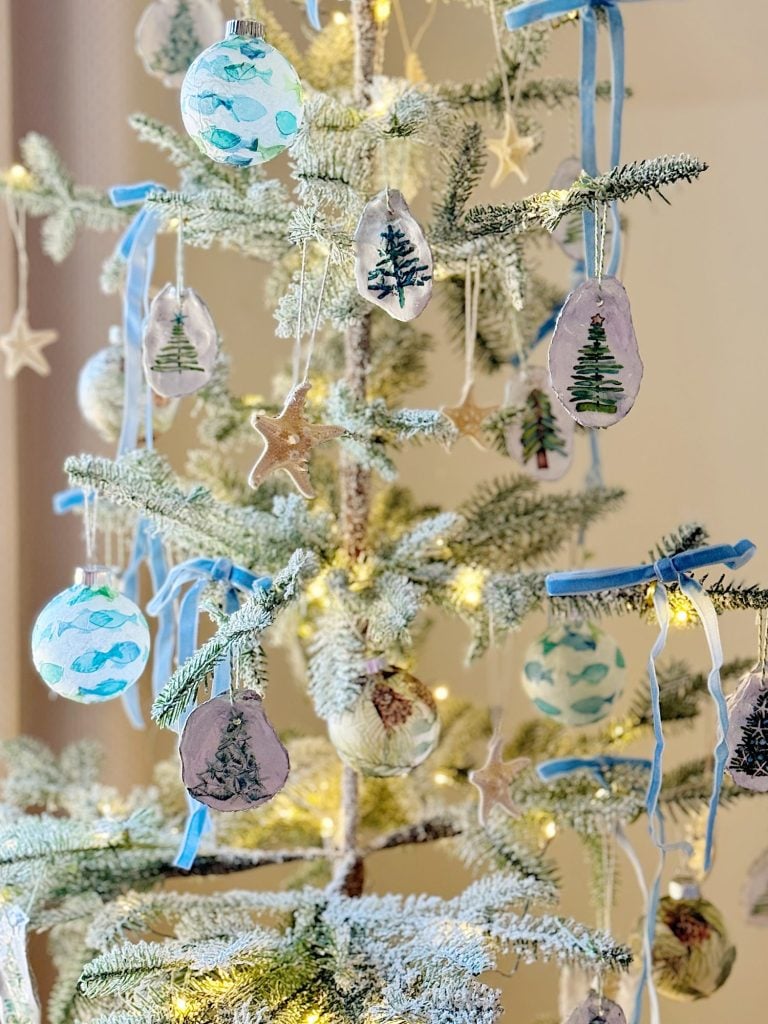 A decorated Christmas tree with tree and star ornaments, blue ribbons, and white lights.