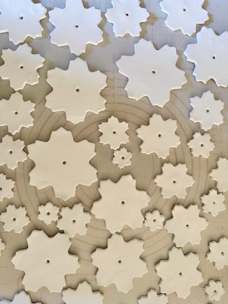 Ceramic snowflake shapes arranged on a textured surface.