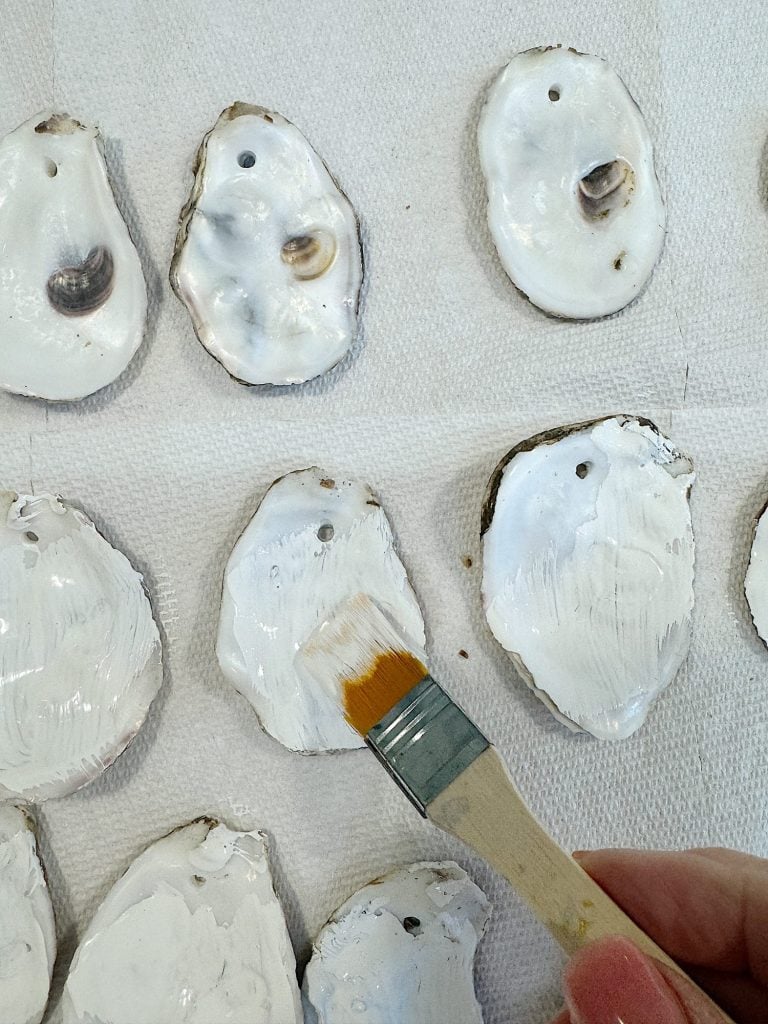 Hand painting white shells with a brush on a paper towel.