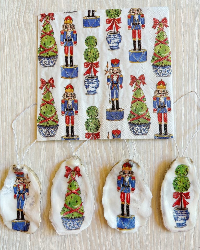 Napkin and oyster shells decorated with nutcracker soldiers and Christmas trees on a light wood surface.