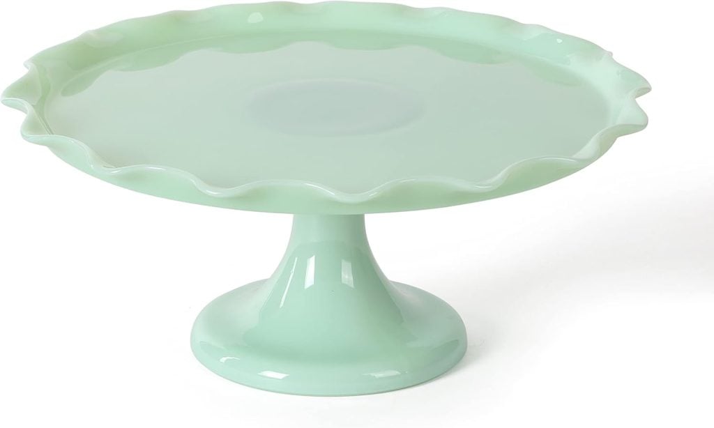 A light green ceramic cake stand with a wavy edge on a single pedestal base.