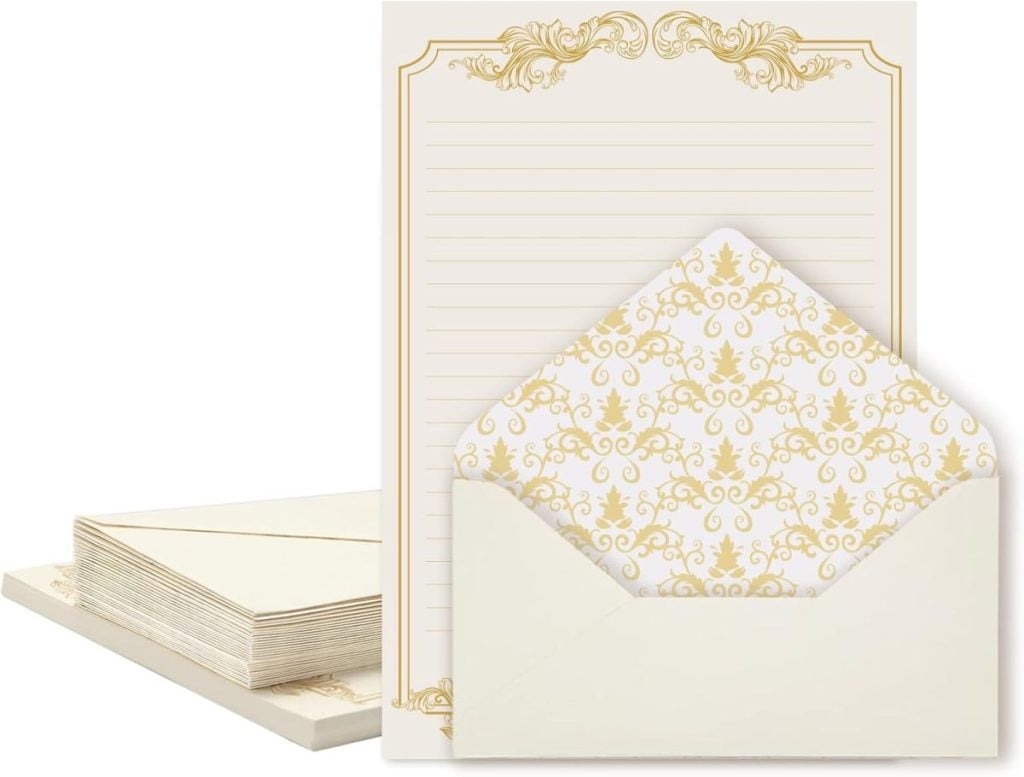 Elegant stationery set with cream-colored paper featuring golden ornate designs, lined for writing, accompanied by matching envelopes with gold patterned interior.