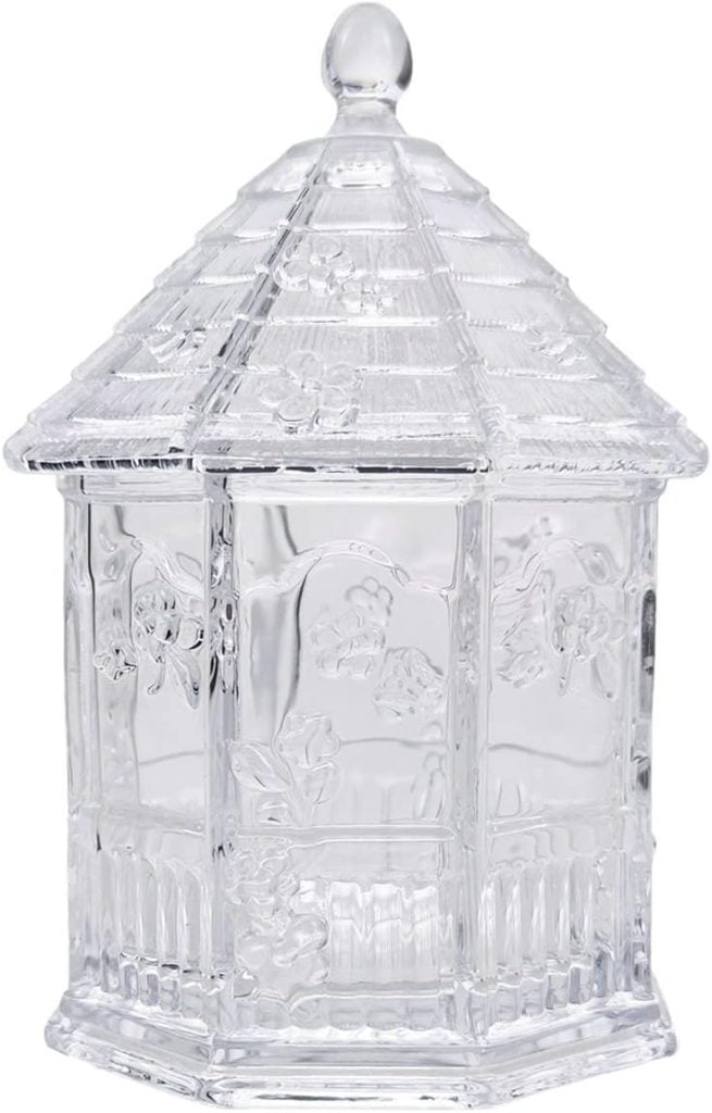 A clear glass jar shaped like a gazebo with a textured roof and floral patterns on the sides.