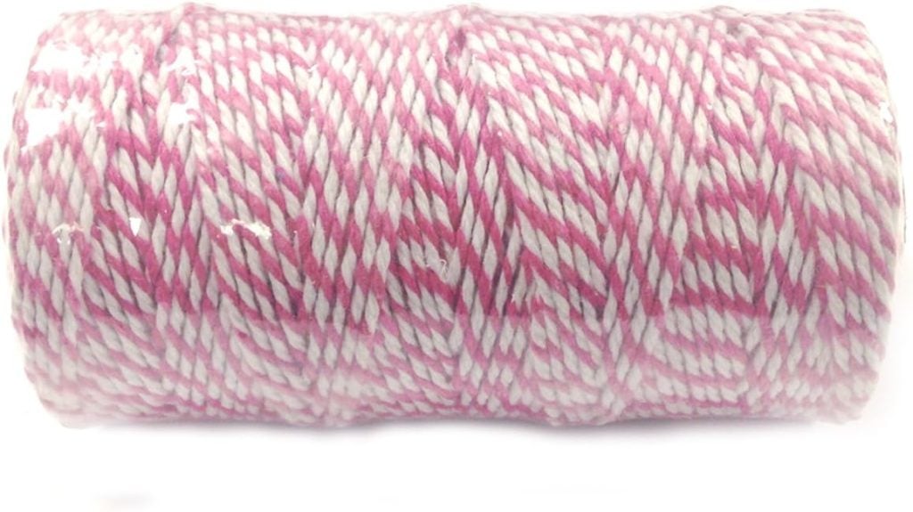 A spool of pink and white twisted twine, wound tightly in a cylindrical shape.