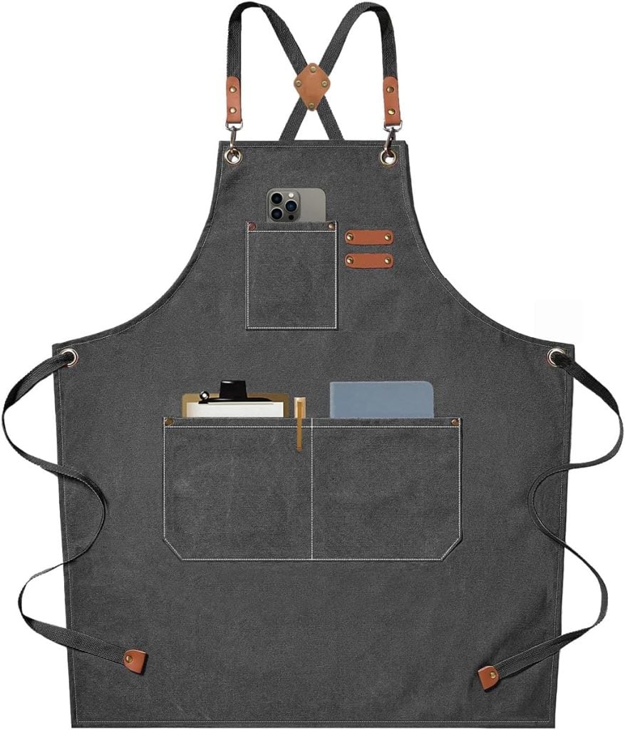 Gray apron with adjustable straps and three front pockets, one holding a phone and others holding paper and pens.