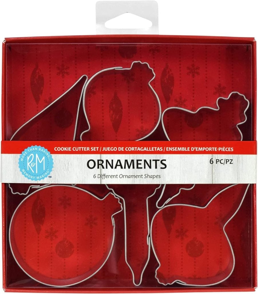 Box of six ornament-shaped cookie cutters, each with a unique design reminiscent of clay ornaments, on a red background adorned with snowflake patterns.