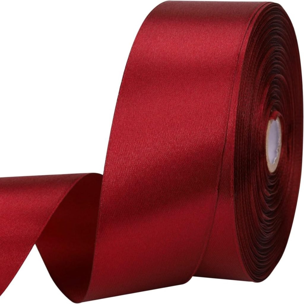 A roll of red satin ribbon partially unrolled, showing its shiny, smooth texture.