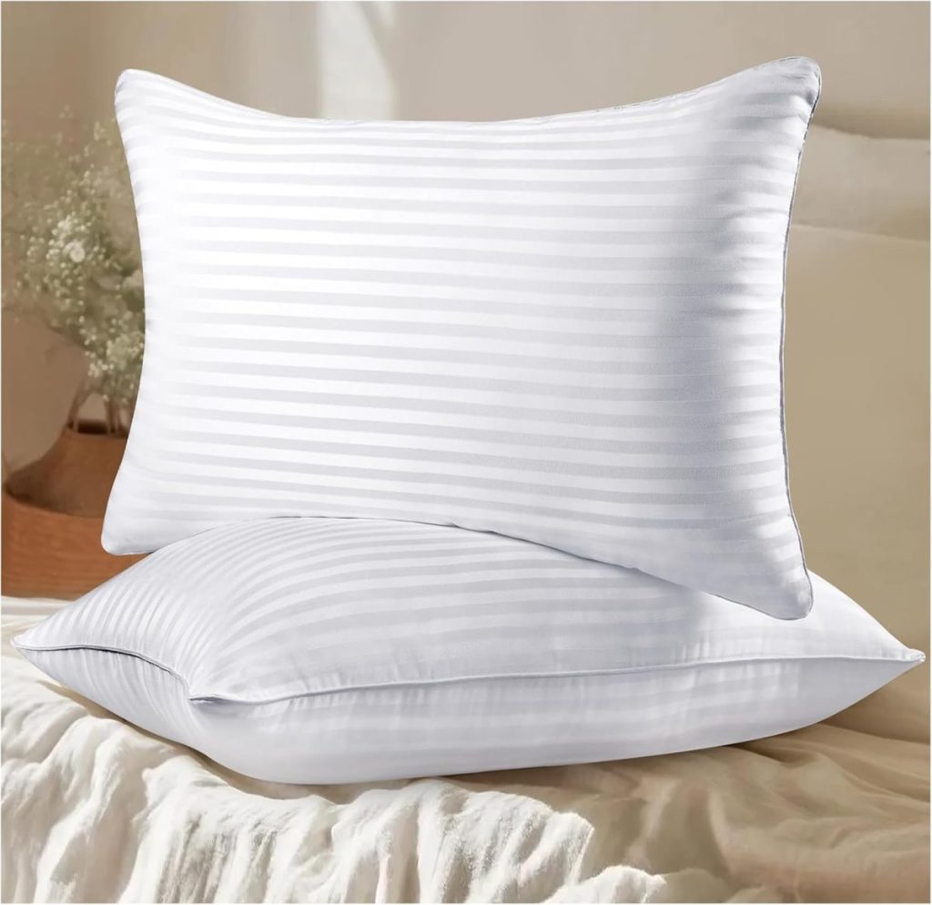 Two white striped pillows stacked on a bed with a blurred background.