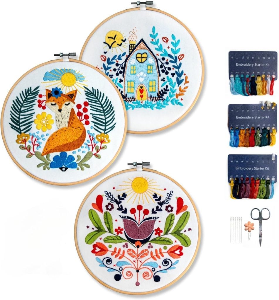 Three embroidery hoops with floral and animal designs, two sets of colored threads, needles, and scissors are displayed.