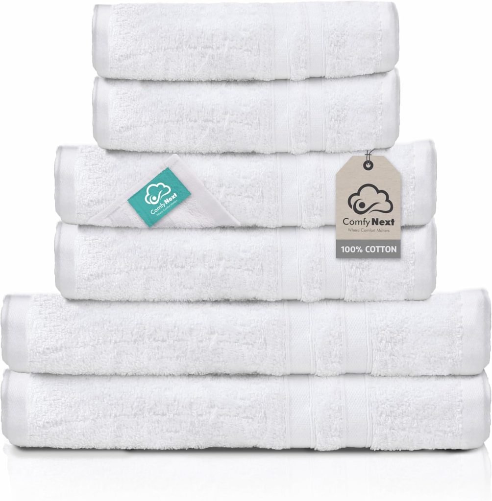 A stack of white cotton towels with tags, featuring the brand "Comfy Next" and a label indicating "100% cotton.