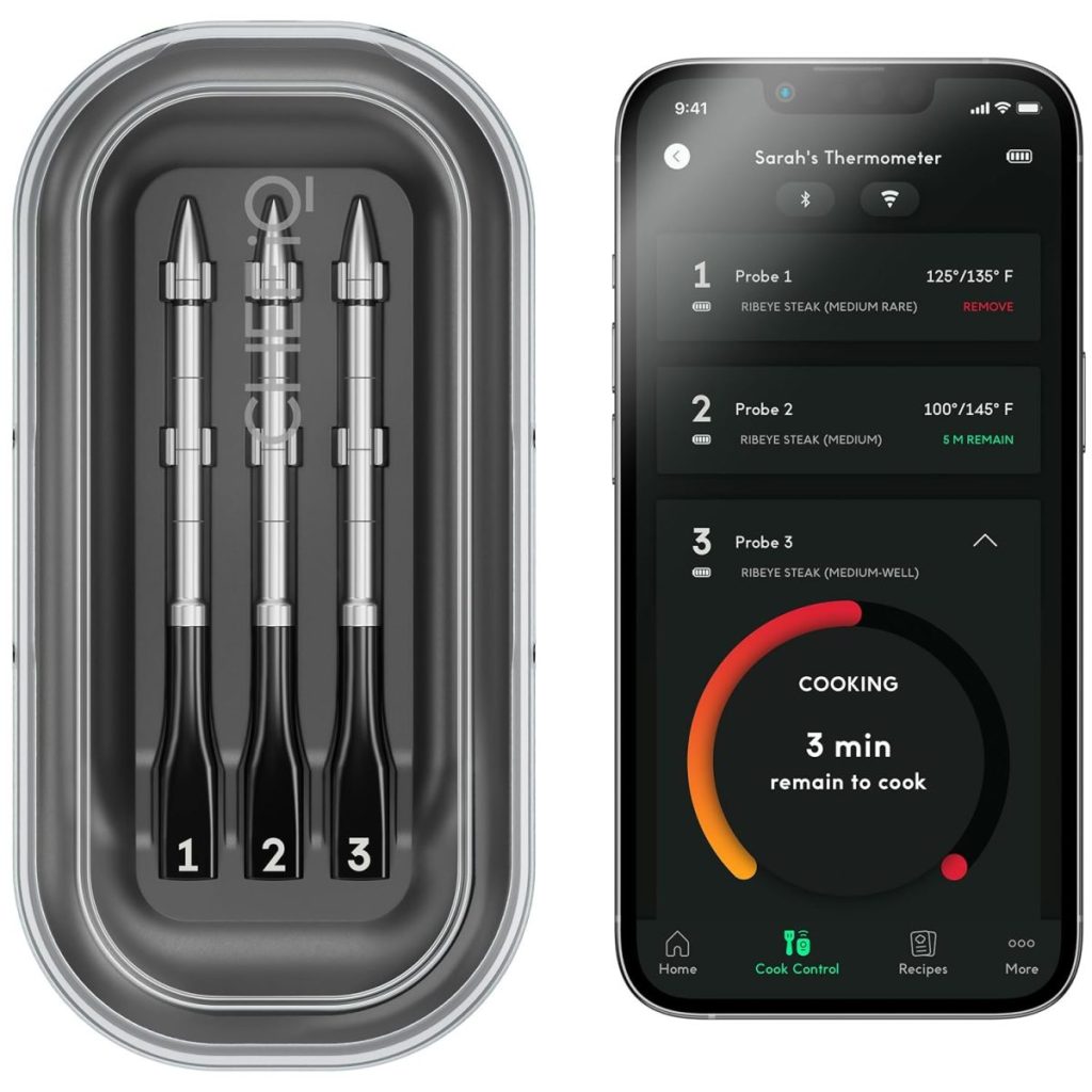 A set of three cooking probes in a case next to a smartphone displaying a cooking app with temperature and time settings for different meats.