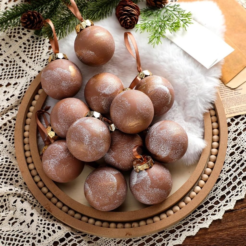 A plate of brown Christmas ornaments with a glittery pattern, surrounded by pine cones and greenery on a lace tablecloth.