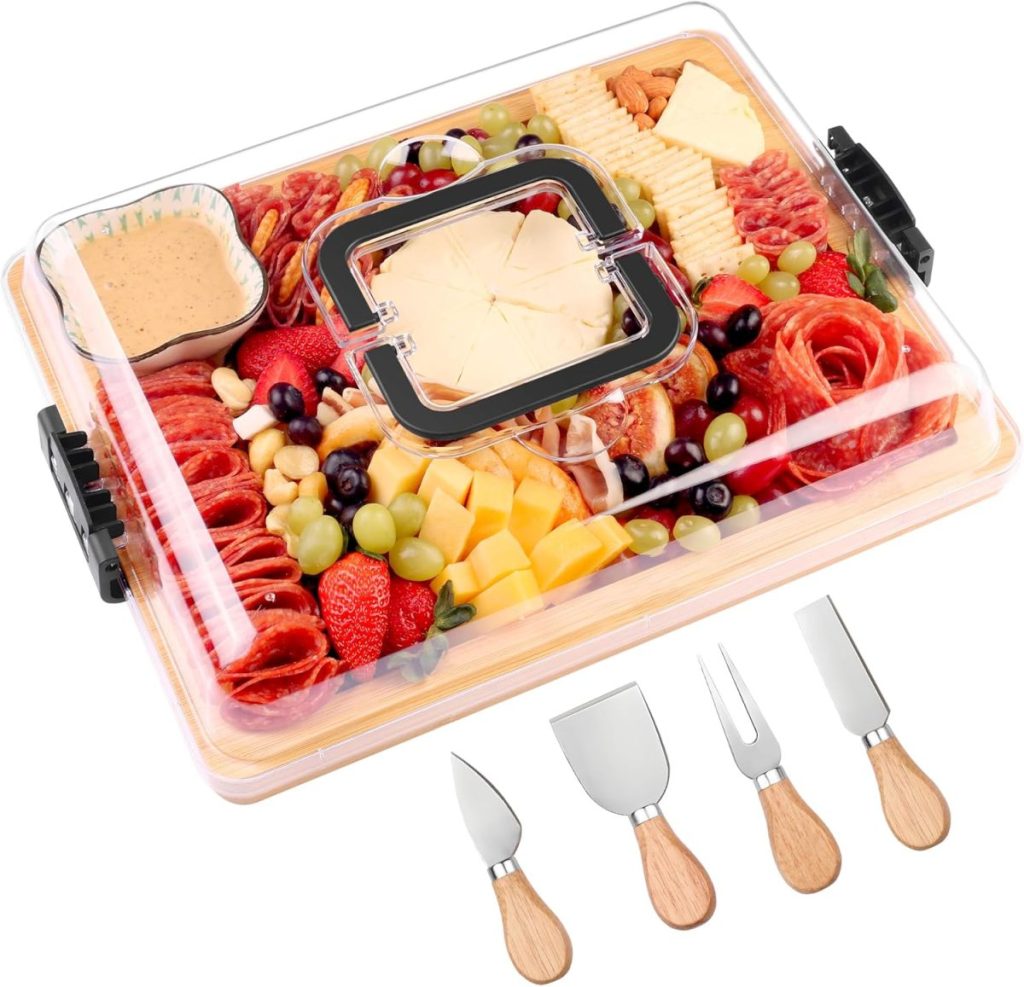A clear-lidded charcuterie board with assorted meats, cheeses, fruits, nuts, and dip sits next to four cheese knives with wooden handles—perfect for sharing during the season of giving.