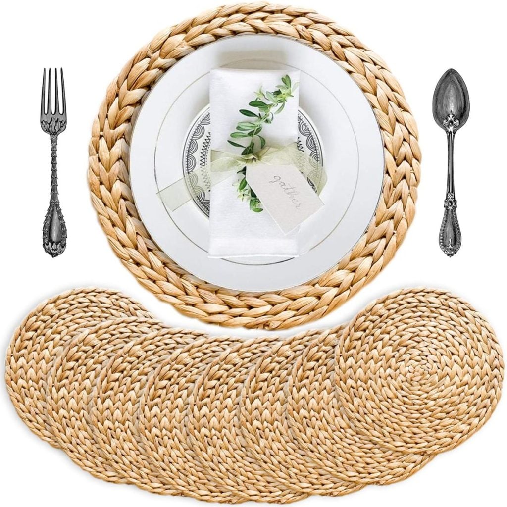 A set of woven rattan placemats, one displayed under a plate, napkin, and cutlery—perfect for adding a cozy touch to your Christmas Morning Breakfast, with the rest neatly arranged in a row below.