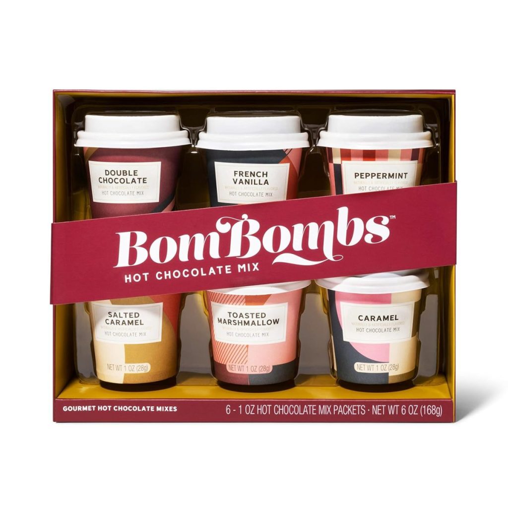 Box set of six hot chocolate mix cups, including flavors: Double Chocolate, French Vanilla, Peppermint, Toasted Marshmallow, and Caramel, labeled "BomBombs Hot Chocolate Mix.