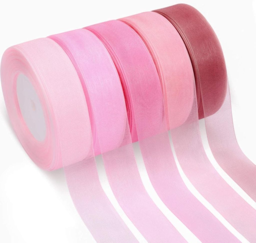 Five rolls of pink and mauve sheer ribbon are displayed, unspooled in a gradient from light to dark.