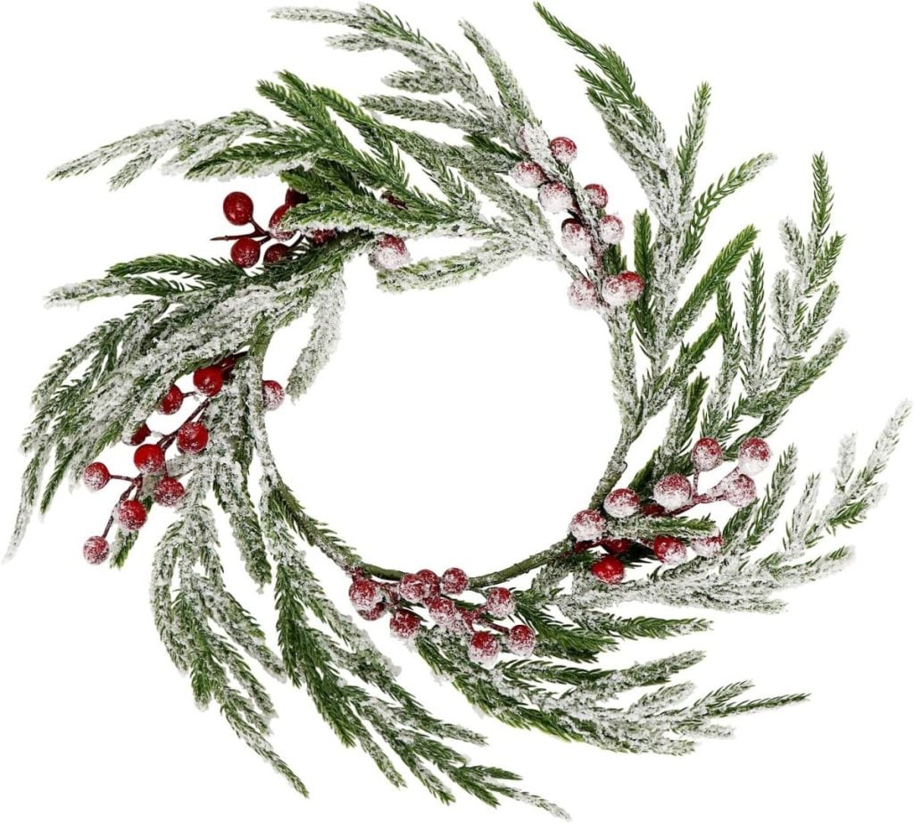 A snowy wreath made of evergreen branches and red berries.