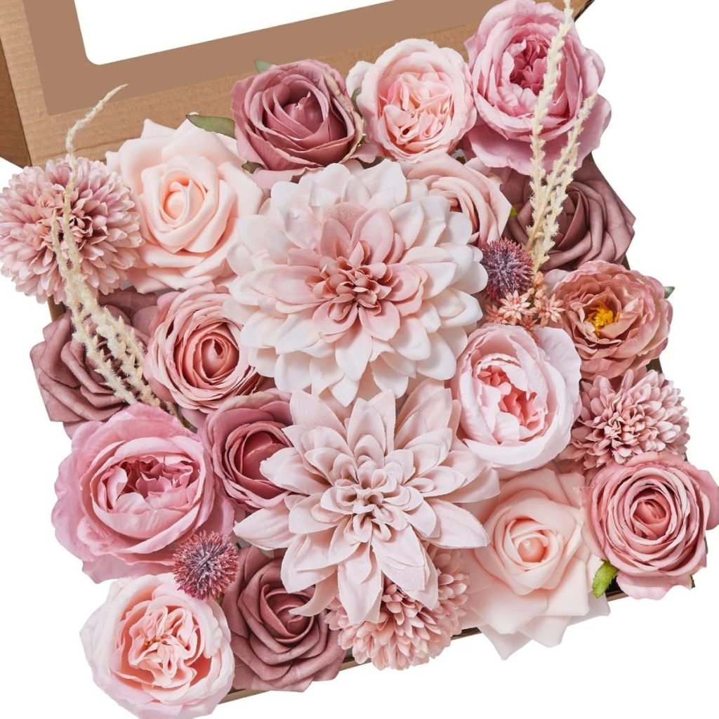 A cardboard box filled with various pink and cream artificial flowers, including roses and dahlias.