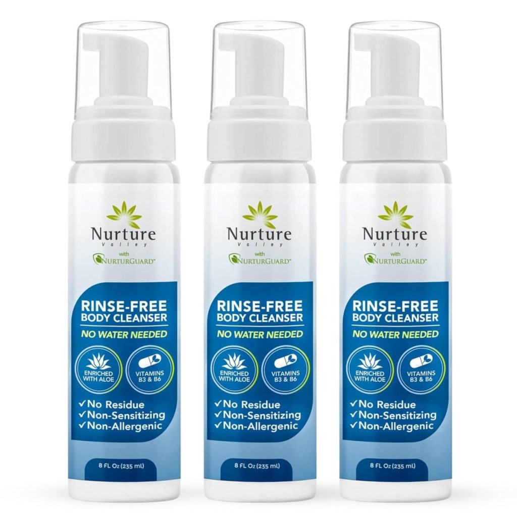 Three bottles of Nurture Rinse-Free Body Cleanser with aloe and vitamins B5 & E. Labels highlight no water needed, residue-free, non-sensitizing, and non-allergenic features.