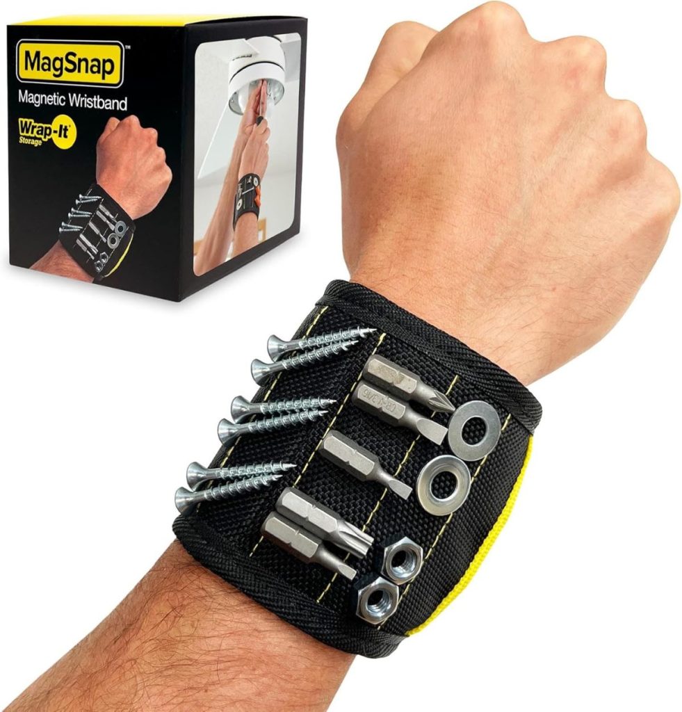 A wrist with a black and yellow magnetic wristband holding screws and nuts, with product packaging in the background.