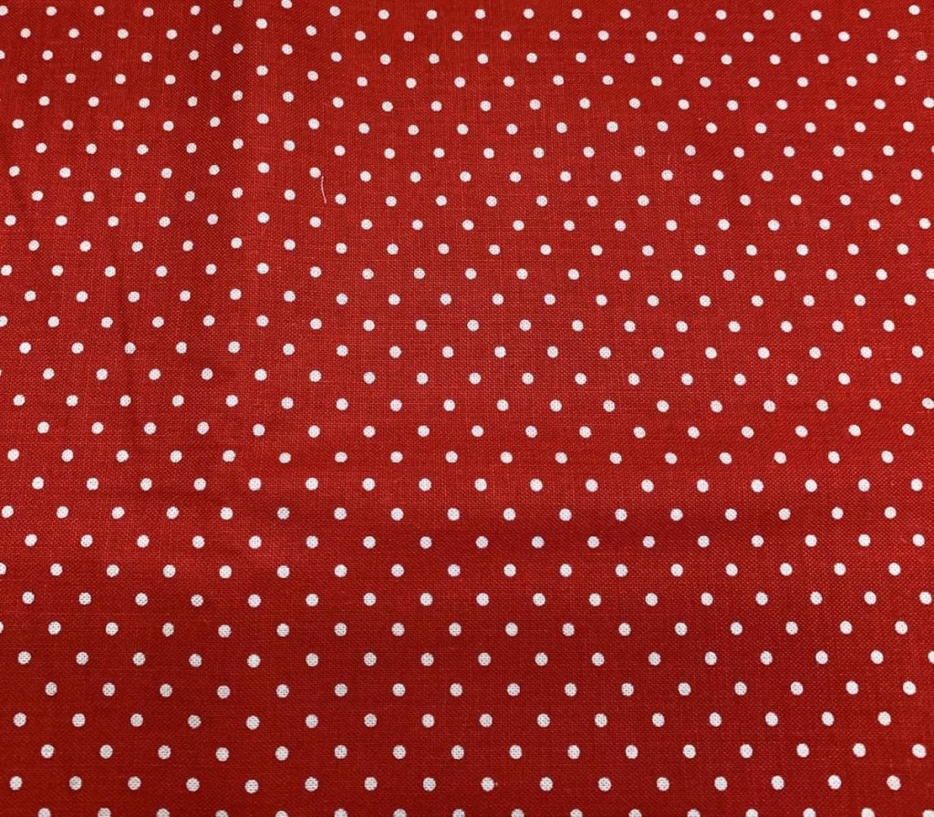 A red fabric adorned with evenly spaced small white polka dots, exuding a sense of Christmas joy.